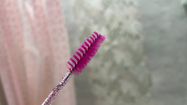A pink brush with a pink handle is held up photo