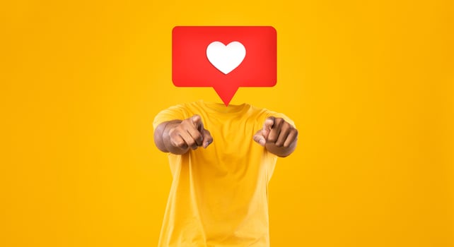 A person wearing a yellow shirt points toward the viewer in a vibrant setting filled with a bright yellow background. Instead their head is heart icon symbolizing likes and affection in social media. photo