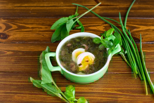 Homemade green borscht with boiled egg and fresh sorrel on a dark wooden table photo