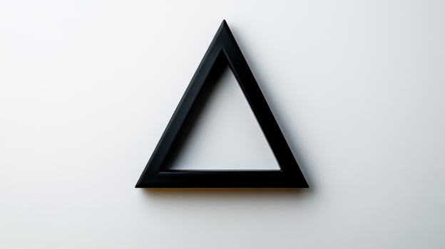 A black triangle shaped object on a white wall photo