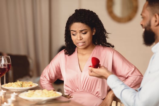 Breakup Concept. Black guy making marriage proposal to unsure woman thinking how to reject offer, frustrated girlfriend don't want to marry her boyfriend, not taking engagement ring, thinking photo