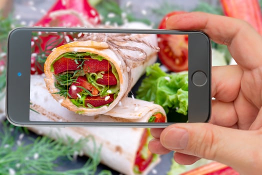 Vegetable roll for healthy lifestyle. Photo smartphone. Smartphone in hand. Roll on the screen.