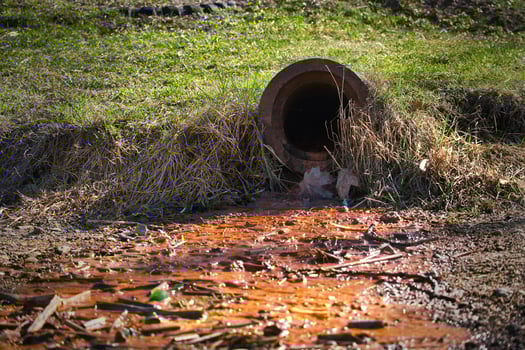 Rusty Drain Pipe Releasing Polluted Water Into Contaminated Soil in a Rural Outdoor Environment photo