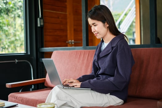 A young woman focused on her laptop in a stylish cafe with a warm, wooden interior and large windows. photo