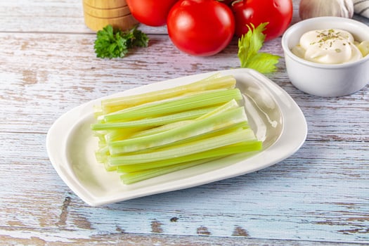 A plate with celery sticks and a bowl of cream photo