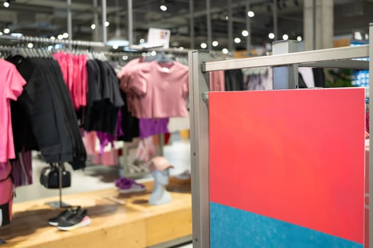 Blank Red Signboard in Fashion Retail Clothing Store. Empty red signboard inside a modern clothing retail store. Ideal for mockup, advertisement. photo