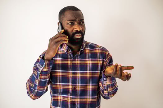 Confused and worried young African American man with a beard, expressing displeasure during a phone conversation. photo
