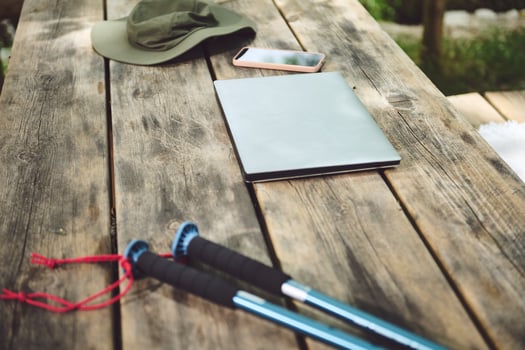 Outdoor Picnic Table With Hat, Laptop, Phone, and Trekking Sticks on Wood photo
