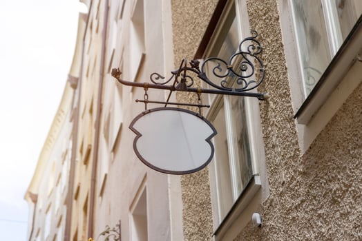 Unique vintage blank signage with wrought iron bracket, perfect for old town shops, cafes, or custom logo mockups in rustic settings. photo