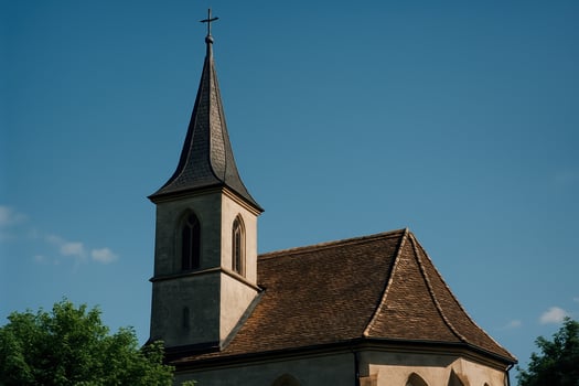 Historic church steeple and tiled roof against a clear blue sky photo