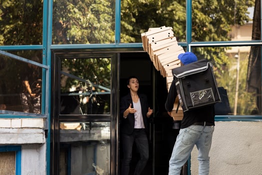 African american worker makes a mistake while he is delivering pizza, stumbling as he trips over and drops the stack of pizza boxes. Confused customer for the poor courier service experience. photo