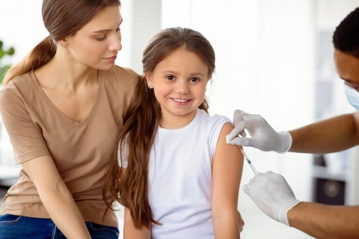 Cute happy girl visiting doctor with her mom, getting injection of covid-19 vaccine at hospital. Parent and child receiving immunization against coronavirus at clinic. Protection against viral disease photo