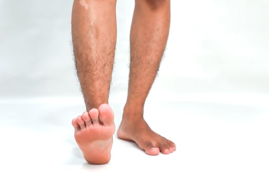 Close-up of Man's Legs and Feet on White Background Showcasing Skin Tone and Texture with Light and Shadow Play photo