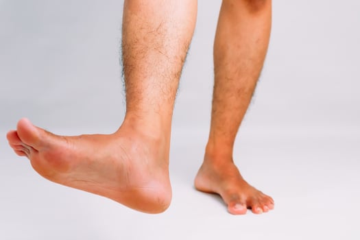 Close-up of a man's legs and feet against a plain background, showcasing foot flexibility photo