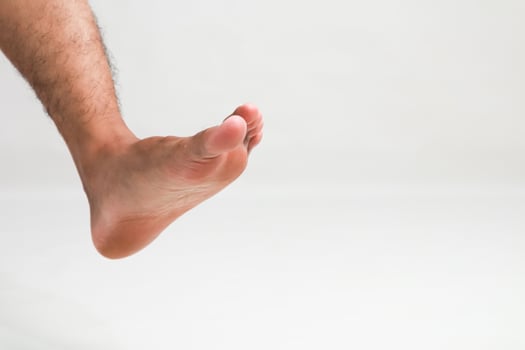 Isolated male foot on a white background showcasing toes, arch, and heel with leg photo