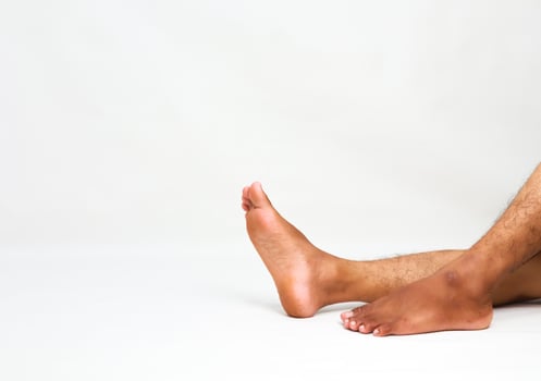 Relaxed dark-skinned man's legs and feet on a white surface, showcasing rest and relaxation for wellness promotions photo