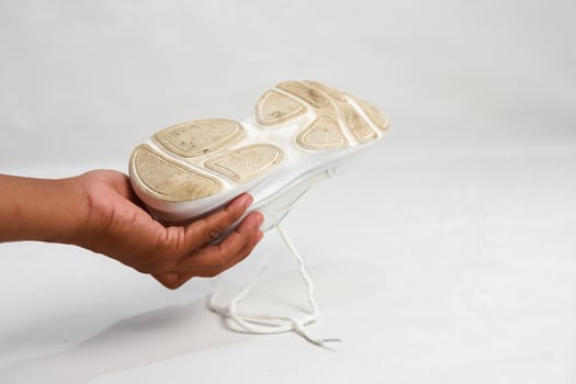 Examining the Sole of a White Athletic Shoe After Use, Highlighting Wear and Tear photo