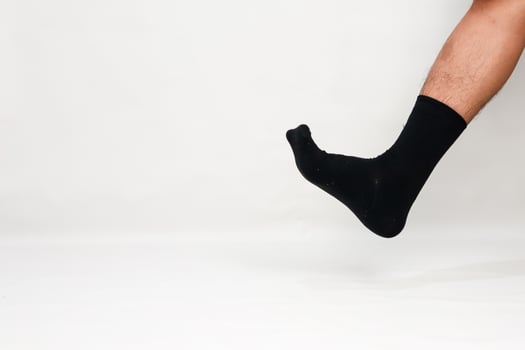 Man's leg wearing a black sock against a plain white background, creating a minimalist and modern visual concept photo