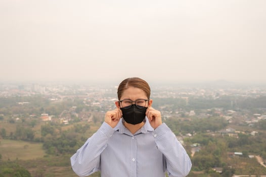 Asian businesswoman wearing N95 mask for protect Bad air pollution covered her town. photo