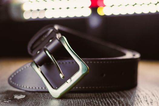 Presenting a Stylish Black Leather Belt with a Modern Buckle Design, beautifully showcased on a Wooden Surface, perfect to elevate any outfit or wardrobe essentials with an elegant touch photo