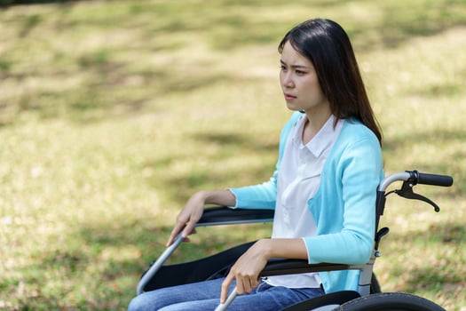 Depressed sad woman in a wheelchair sitting on the grass photo