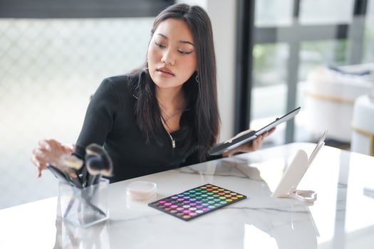 Beauty influencer is sitting at a table with a tablet and a palette photo