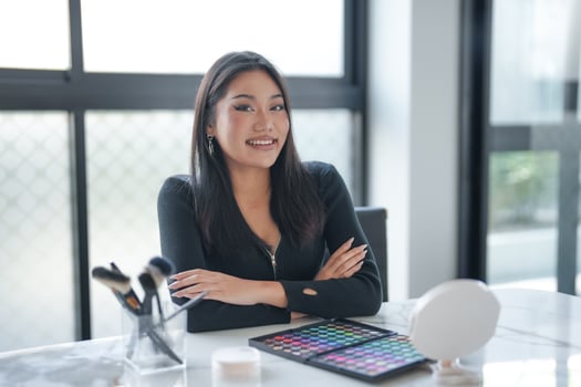 Beauty influencer sitting at a desk with makeup products photo