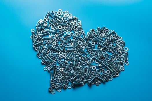 The metal heart is isolated on a blue background. The concept of cold bloodedness. Attachment material photo