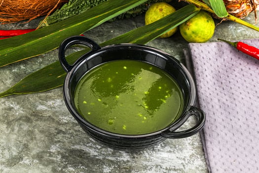 A bowl of green soup with a coconut and some other vegetables photo