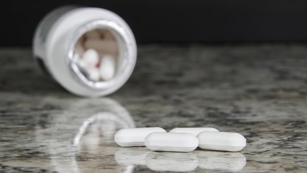 Pills spilled from a prescription bottle onto a granite countertop photo
