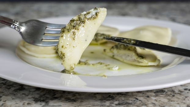 Delicious homemade ravioli served with pesto sauce on a white plate in a cozy kitchen setting photo