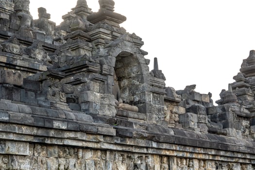 A headless Buddha statue sits in a stone niche on Borobudur temples ancient upper terrace. photo