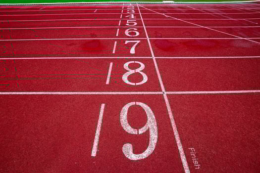 Horizontal wide shot of running track finish line, lanes 1 to 9 red surface and white stripe, symbolizing competition, motivation and victory. photo