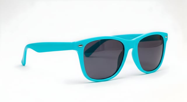 A pair of turquoise sunglasses with dark lenses isolated against a black background in studio shot photo