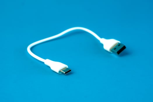 A short white USB to microUSB cable on a blue background. Ideal for charging and data transfer for smartphones, tablets, and electronic devices. Compact and portable for everyday use. photo