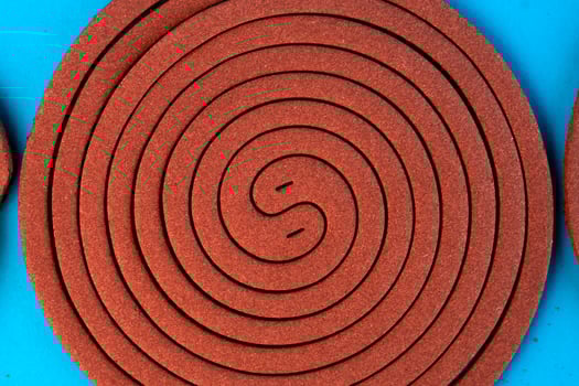A mosquito coil in a spiral shape on a blue background. Insect repellent for outdoor and indoor use, designed to keep mosquitoes away and provide protection from bites. photo