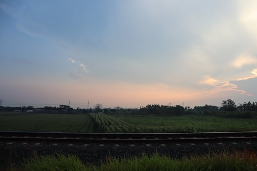 A train is traveling through a field with a sky in the background photo