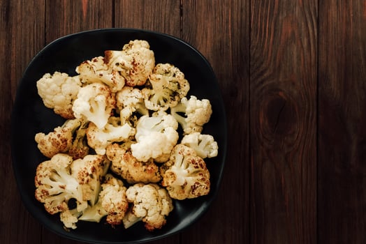 Roasted cauliflower served in a black bowl on a rustic wooden table photo
