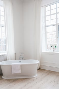 Bright and airy bathroom with white bathtub and natural light from large windows photo