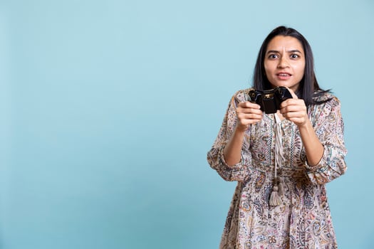 Confident thrilled gamer smiling and paying attention on the competition, e sport tournament on her mobile phone. Young indian woman enjoying interactive gameplay in studio. photo