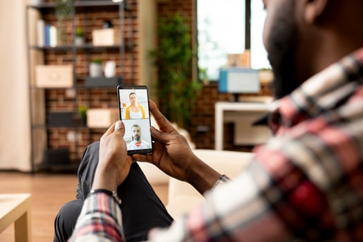 Self employed black man using cellphone for virtual meeting with potential investors. African american entrepreneur on call, seeking financial advice from team of caucasian accountants. photo