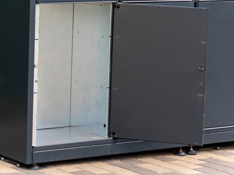 A storage cabinet with an open door reveals a clean interior space, suitable for organizing items. Located in an urban setting, it provides convenient storage solutions photo