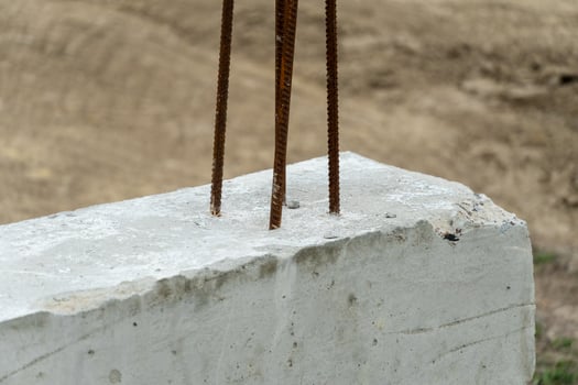 Exposed rebar protrudes from a concrete block, indicating ongoing construction work in a rural area under clear skies during the afternoon photo