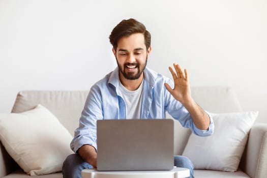 Online Meeting. Cheerful Arab Man Making Call With Laptop At Home, Friendly Eastern Guy Waving Hand At Computer Webcam, Greeting Somebody, Smiling Male Enjoying Distant Communication, Free Space photo
