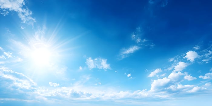 Bright Sun Shining in Blue Sky with Fluffy White Clouds photo