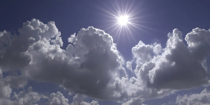 Bright Sun Shining Through Fluffy Cumulus Clouds Blue Sky Background photo