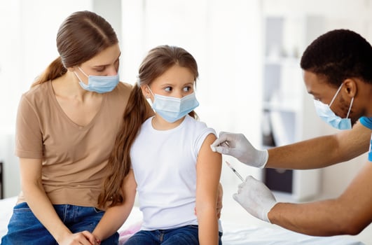 Mother and daughter in medical masks getting vaccinated against covid-19, doctor giving injection of coronavirus vaccine at hospital. Antiviral immunization campaign concept photo