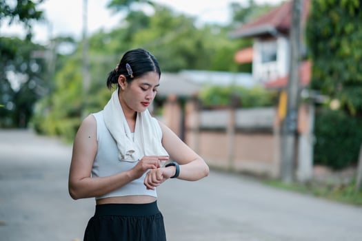 Young woman using a smartwatch while exercising outdoors in a suburban area, focusing on fitness and technology. photo