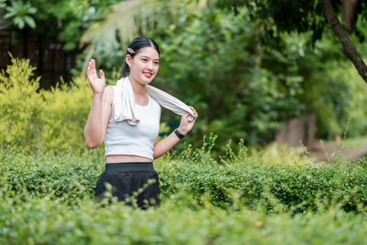 A young woman in athletic attire smiles while exercising in a vibrant, green park, showcasing a healthy and active lifestyle. photo