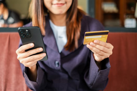 Close-up of a woman using a smartphone and credit card for online shopping in a relaxed cafe environment. photo